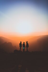 silhouette of three people up on mountain cliff