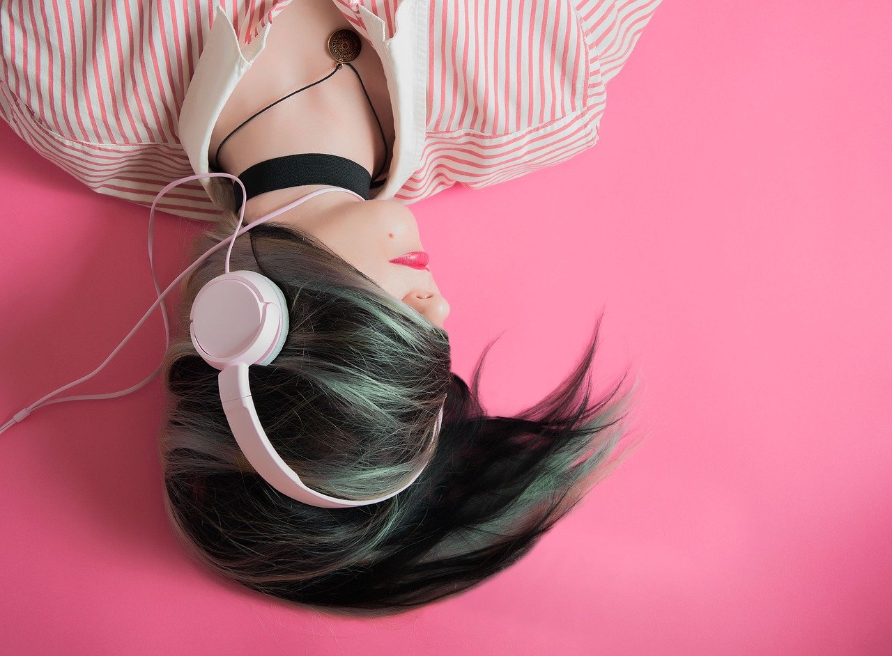 girl listening to headphones on pink background