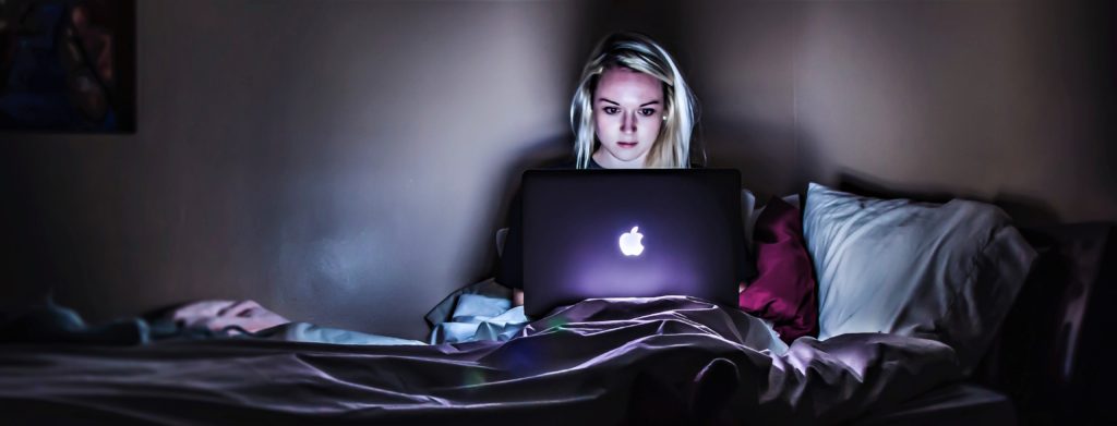workaholic woman working at night on laptop in bed